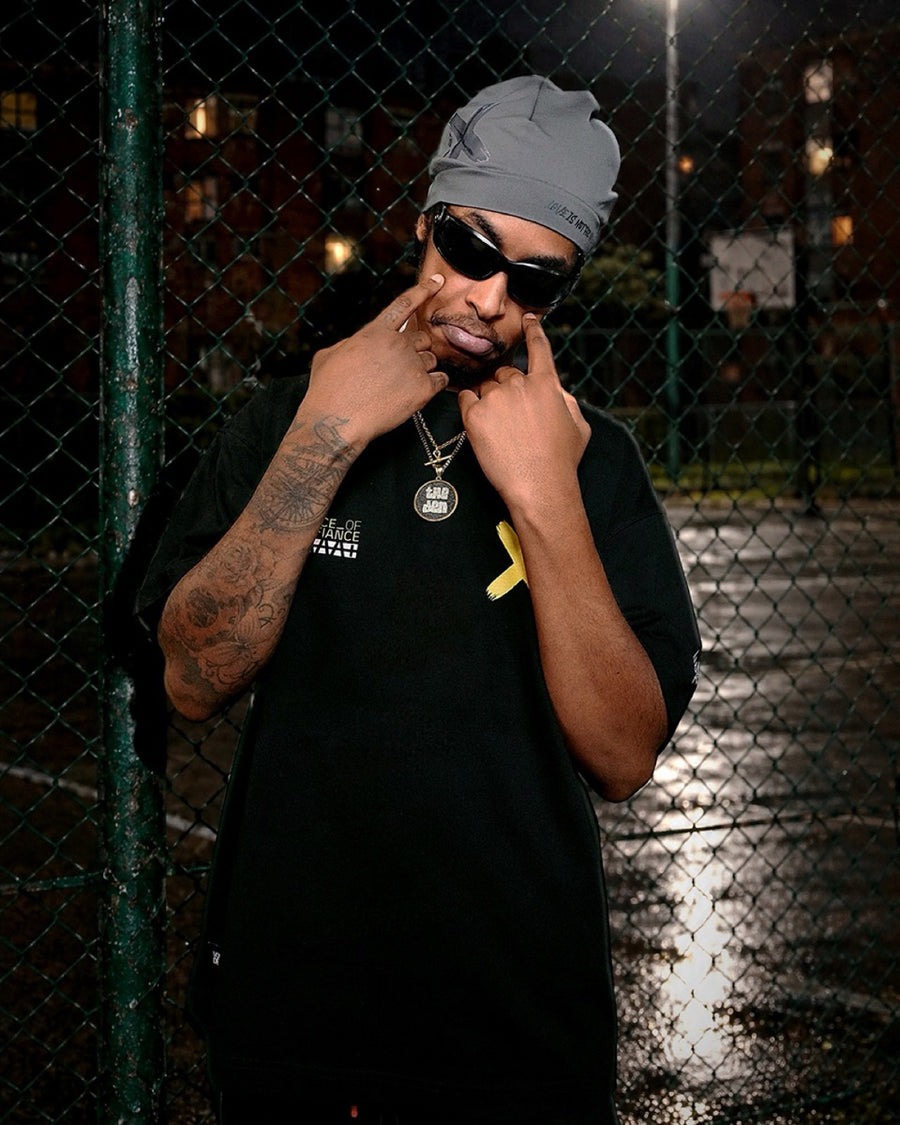 One of the collective in a grey beanie and shades by a wet cage court at night.